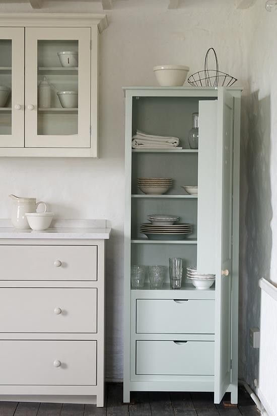 a tall cabinet in the corner of a room with dishes on it and glass doors