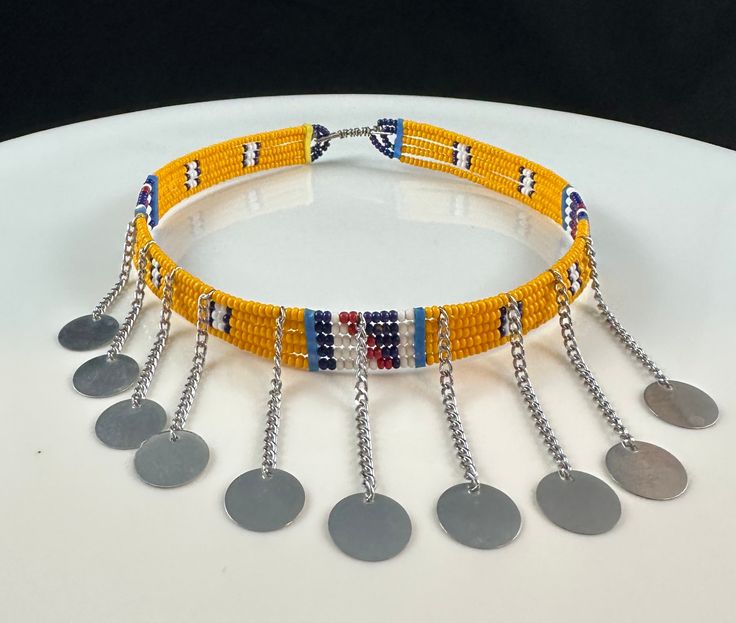 "Handmade by artisans from the Maasai Tribe.  Adjustable metal closure. Metal fringe measures about 1-2\" (inches) in length. Maasai beadwork is not just decorative, but a vital aspect of Maasai culture. Jewelry is made and worn to indicate age and social status as well as to mark important events. Each Color also have meaning." Traditional Beaded Fringe Necklace, Traditional Adjustable Beaded Fringe Necklaces, Traditional Adjustable Beaded Fringe Necklace, Adjustable Bohemian Silver Beads, Bohemian Adjustable Silver Beads, Adjustable Beaded Chain Beads For Festive Occasions, Adjustable Beaded Chain For Festive Occasions, Gold Jewelry With Beaded Fringe For Festival, Traditional Large Beads For Choker