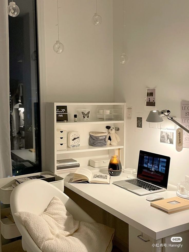 a laptop computer sitting on top of a white desk next to a book shelf filled with books