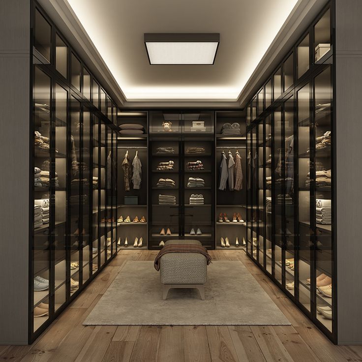 a large walk in closet with lots of clothes on shelves and lights above the doors