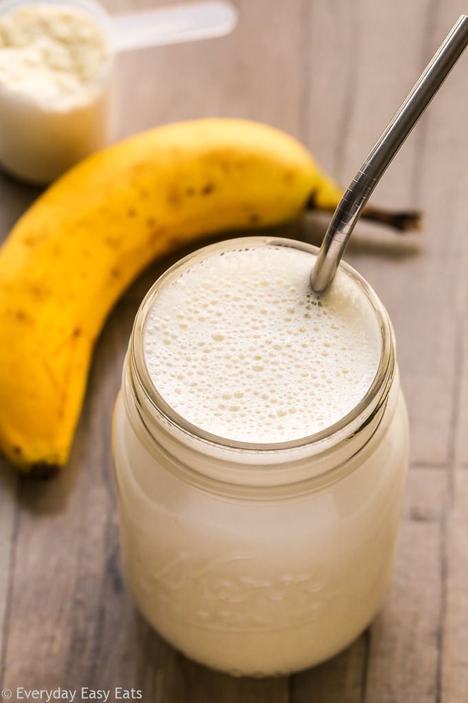 a banana sitting next to a mason jar filled with milk