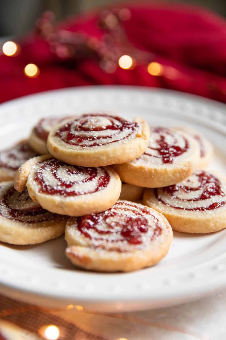 a white plate topped with cookies covered in powdered sugar next to a christmas tree