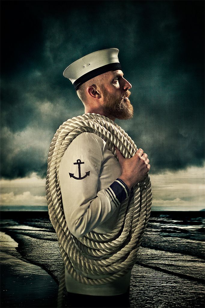 a man wearing a sailor's hat and holding a rope with an anchor on it