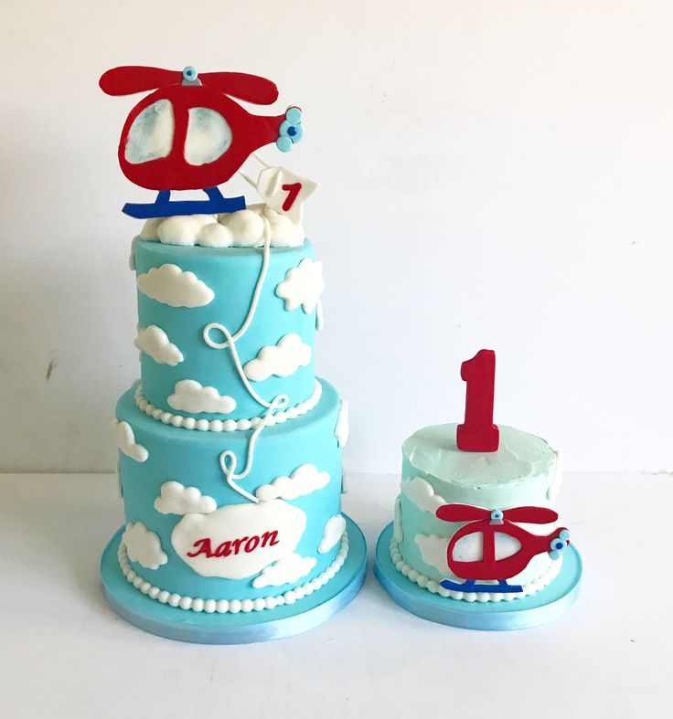 a blue cake with red and white decorations on it's top, sitting next to another one