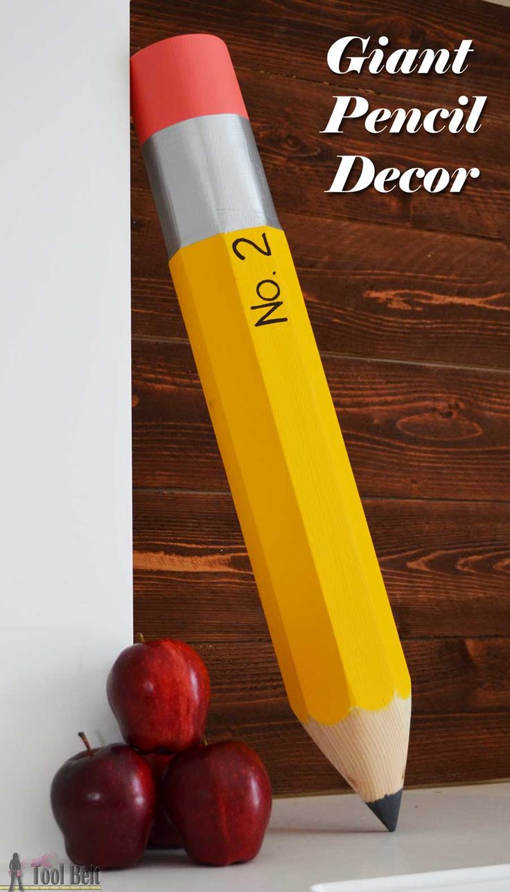 a pencil sitting on top of two apples next to a wooden sign that says giant pencil decor