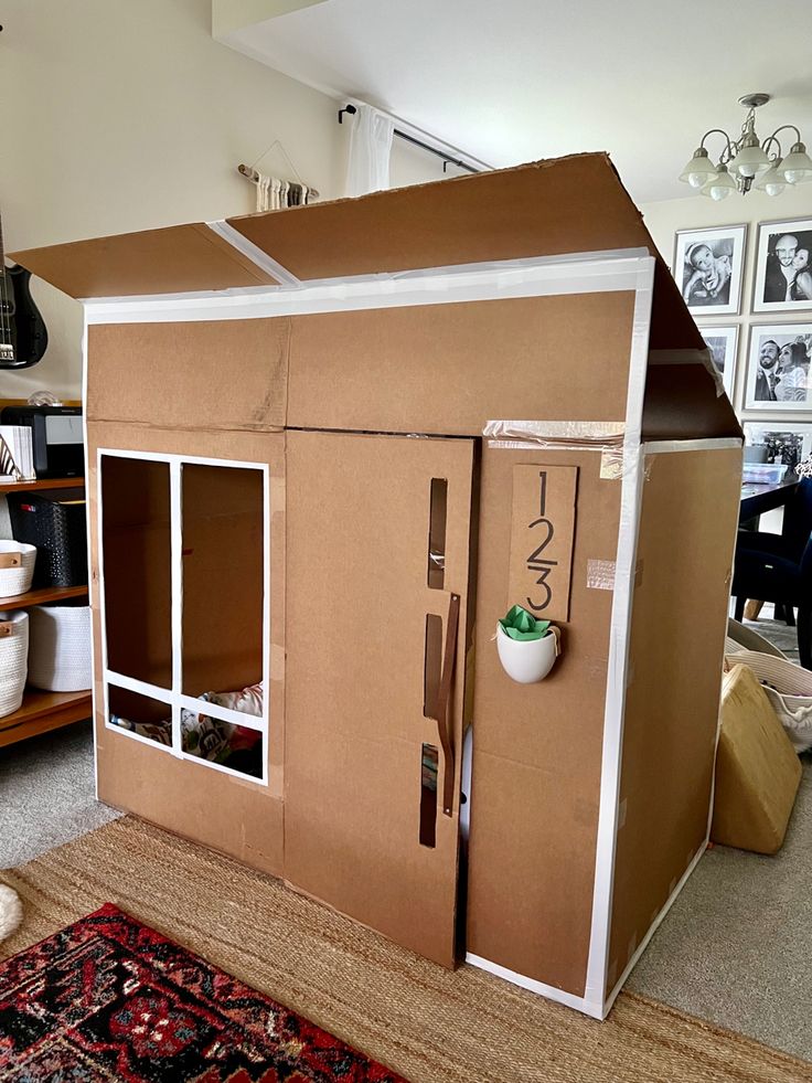 a cardboard doll house with its doors open and shelves on the floor in front of it