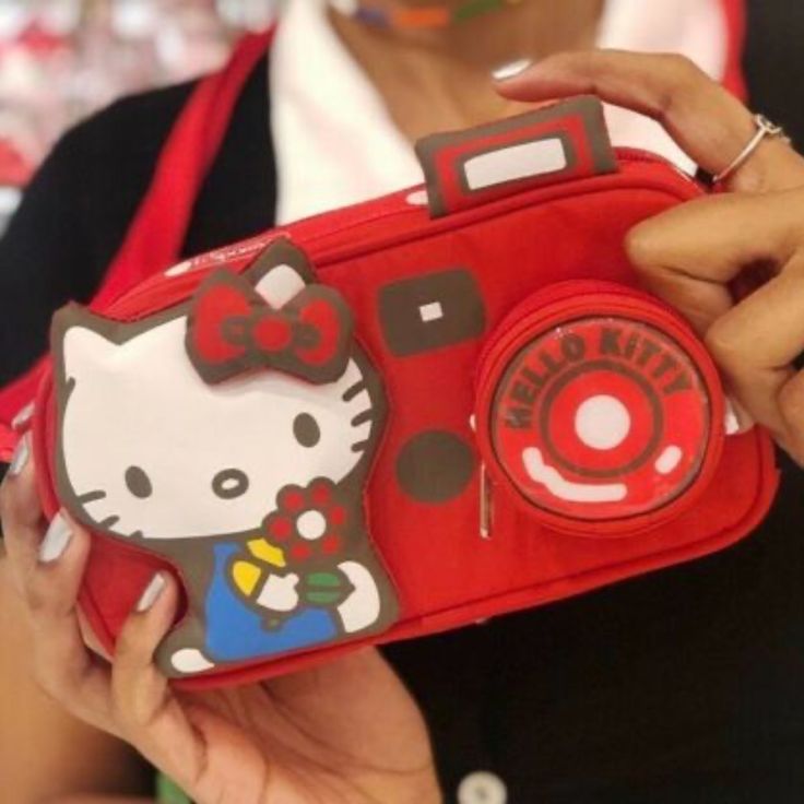 Picture Yourself In This Supercute Hello Kitty Camera Bag! Made In Collaboration With Our Friends Le Sportsac To Celebrate Hello Kitty's 45th Anniversary, This Product Is Limited Edition. 3.75" H X 7" W X 2" Features A Zip Top Main Closure, Exterior Front Coin Pocket With Zip Closure, And Interior Back Wall Open Pocket. There Are Also Two Strap Options: Attached 14" Short Strap, Plus A 40" Long Extension Strap With Quick Release Clips On Each End (For Crossbody Wear). Cute Red Satchel Bag, Cute Red Shoulder Bag, Red Handheld School Bag, Red School Bag With Detachable Strap, Cute Red Satchel For Everyday Use, Cute Red Satchel For Daily Use, Cute Red Shoulder Bag For Everyday Use, Portable Red Rectangular Pouch, Cute Red Rectangular Satchel