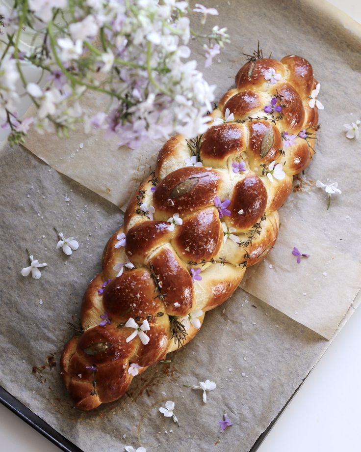 some bread is sitting on a piece of wax paper with flowers in the back ground