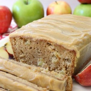 a loaf of apple cake with frosting on a plate next to apples