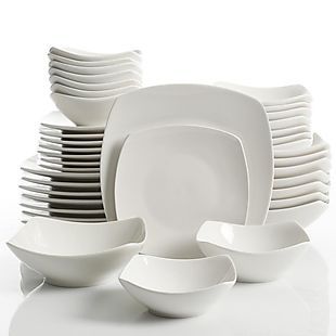 a stack of white plates and bowls on a table