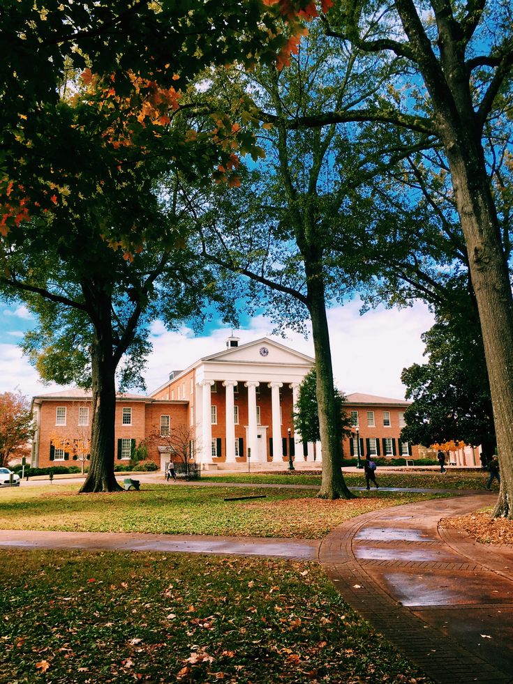 an old building with columns and pillars in the middle of it surrounded by leafy trees