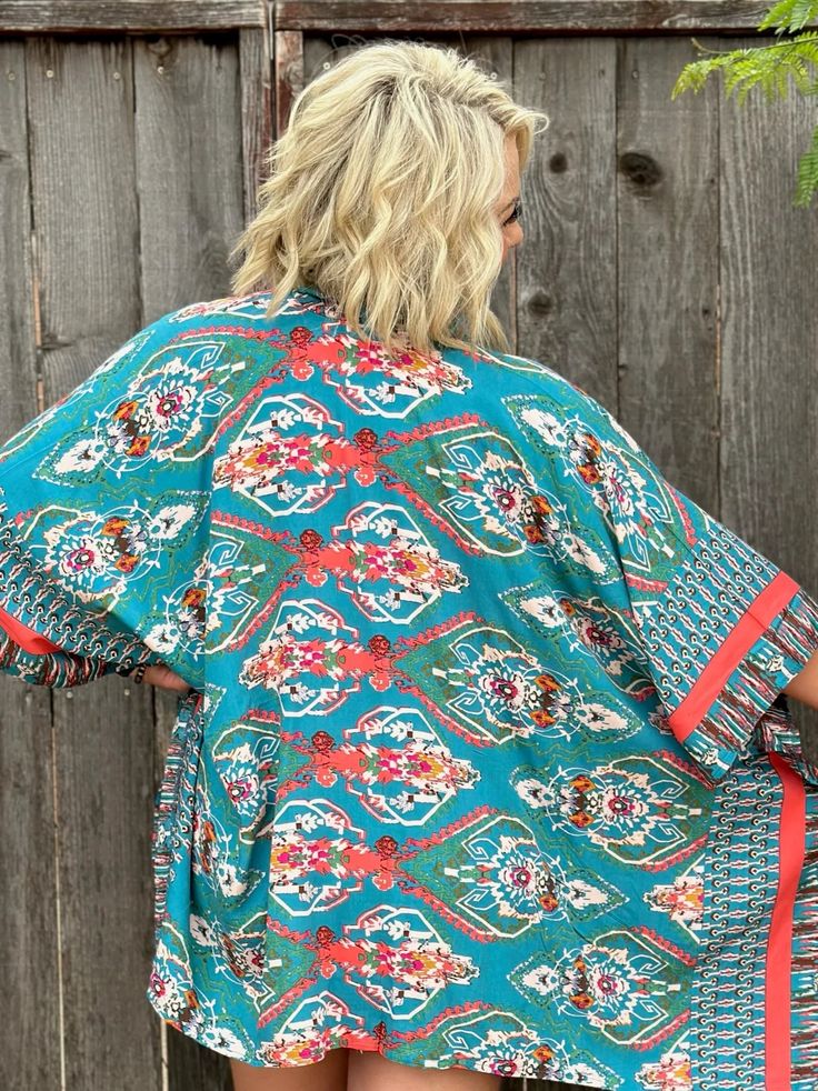 This kimono is a showstopper! Goes with a tank, a statement tee, or even great over a swimsuit! In turquoise or red. Both stunning! 100% Viscose Want to view this on the *Live* Sizing & Styling Guide?! Watch it in the photo section above or click here! *You will need to scan through to find this specific item on the video. Rachel is a size 8, Kristine is a 14/16. Blue Boho Print Kimono For Spring, Casual Blue Kimono For Festival, Summer Festival Blue Kimono, Summer Kimono With Vibrant Print, Red One-size Summer Kimono, Blue Bohemian Top With Kimono Sleeves, Vibrant Print Kimono For Vacation, Bohemian Tops For Poolside, Turquoise Floral Print Top For Summer