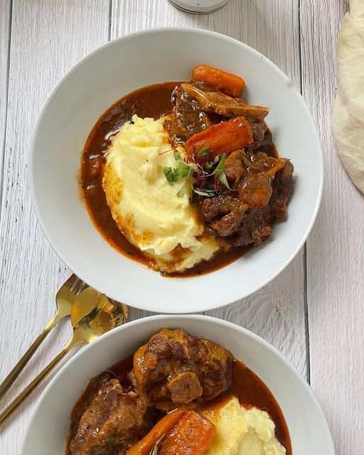 two white bowls filled with meat and mashed potatoes