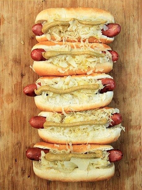 four hot dogs with sauerkraut and mustard on them