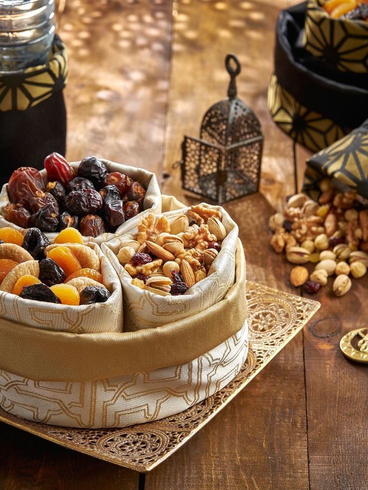 two baskets filled with nuts and dried fruit on a wooden table next to other items