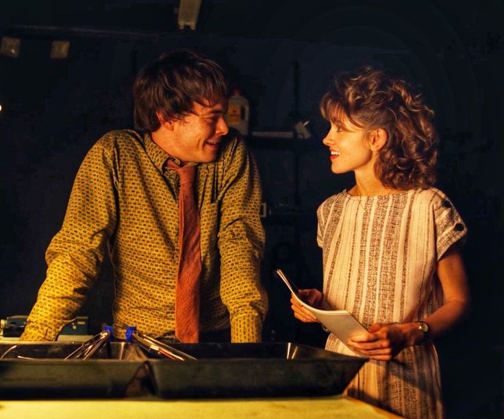 a man and woman standing next to each other in front of a table with papers