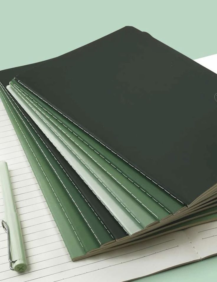 a stack of notebooks and pen sitting on top of each other