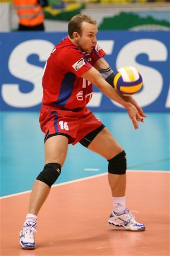 a man standing on top of a tennis court holding a ball in one hand and a volleyball in the other