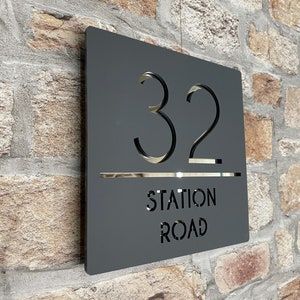 a sign on the side of a brick wall that reads 32 station road with black letters