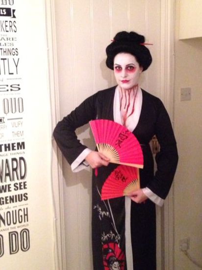 a woman dressed up as geisha holding a fan and posing for the camera with her hands on her hips