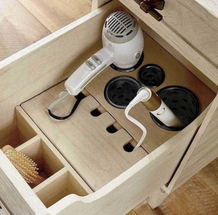 an electric hair dryer is sitting in a drawer with other items on the drawers