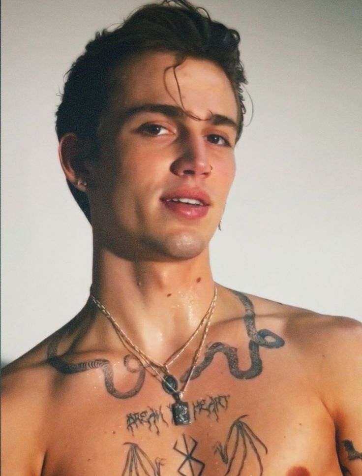 a shirtless man with tattoos on his chest is looking at the camera while wearing a necklace