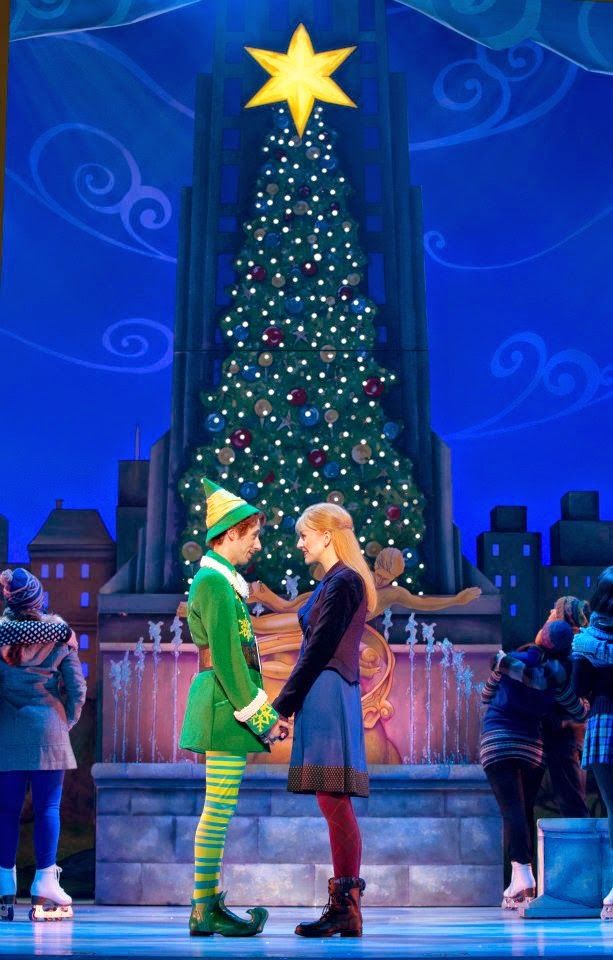 a man and woman standing next to each other in front of a lit christmas tree