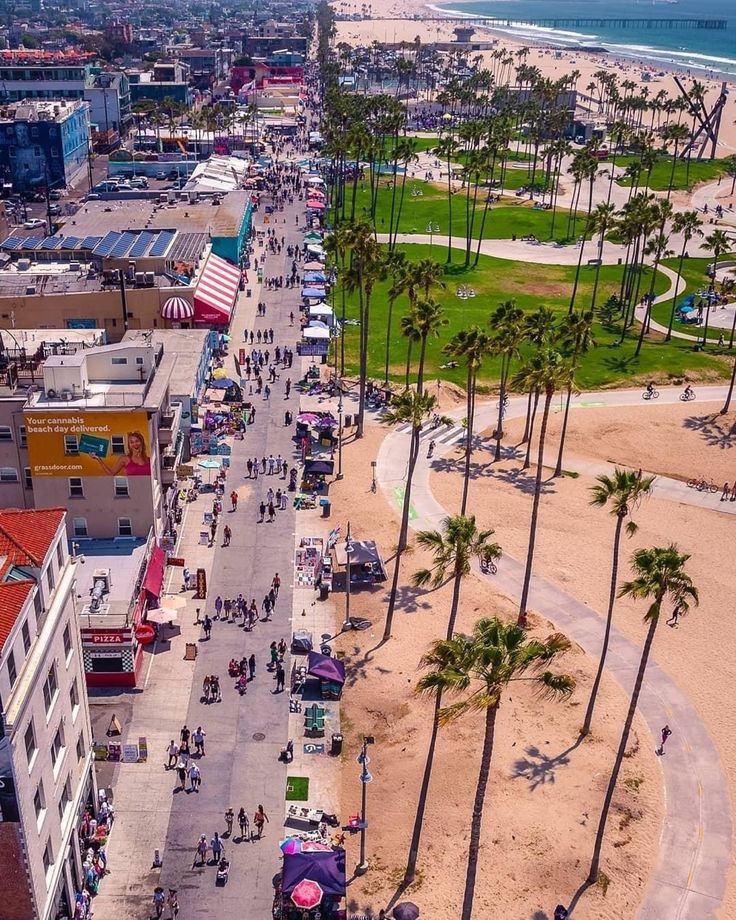 an aerial view of a beach with palm trees and people walking on the sand in front of buildings