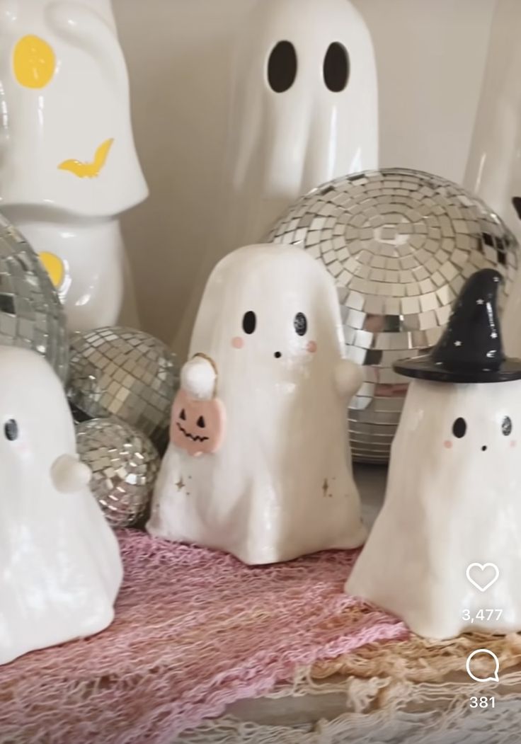 some white ghost figurines sitting on a table with disco balls in the background