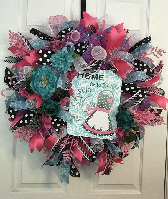 a pink and blue wreath on the front door with a welcome home sign attached to it