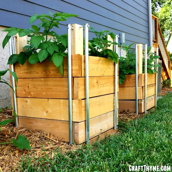 a row of wooden planters with plants growing in them on the side of a house