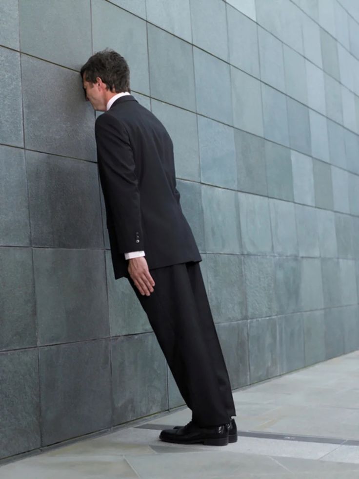 a man in a suit leaning against a wall