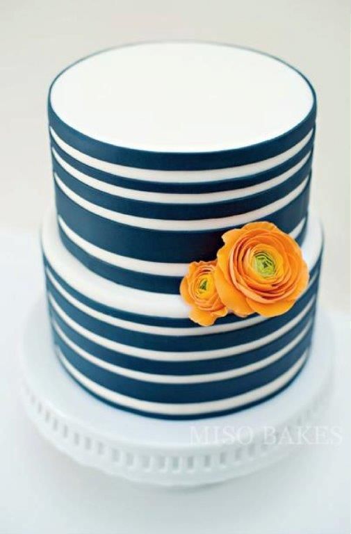 there is a blue and white striped cake with orange flowers on the top, sitting on a plate