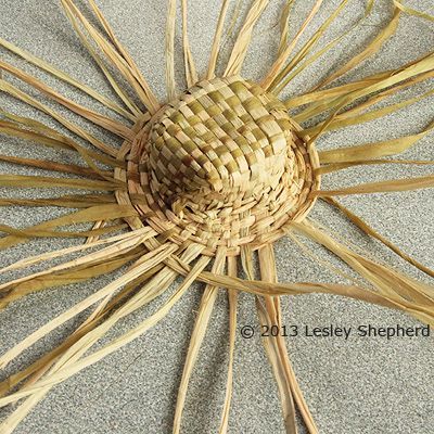 a straw sun umbrella laying on the sand