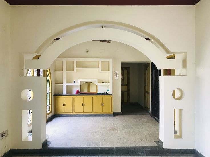 an archway leading into a kitchen with yellow cabinets and counter tops on either side of the room