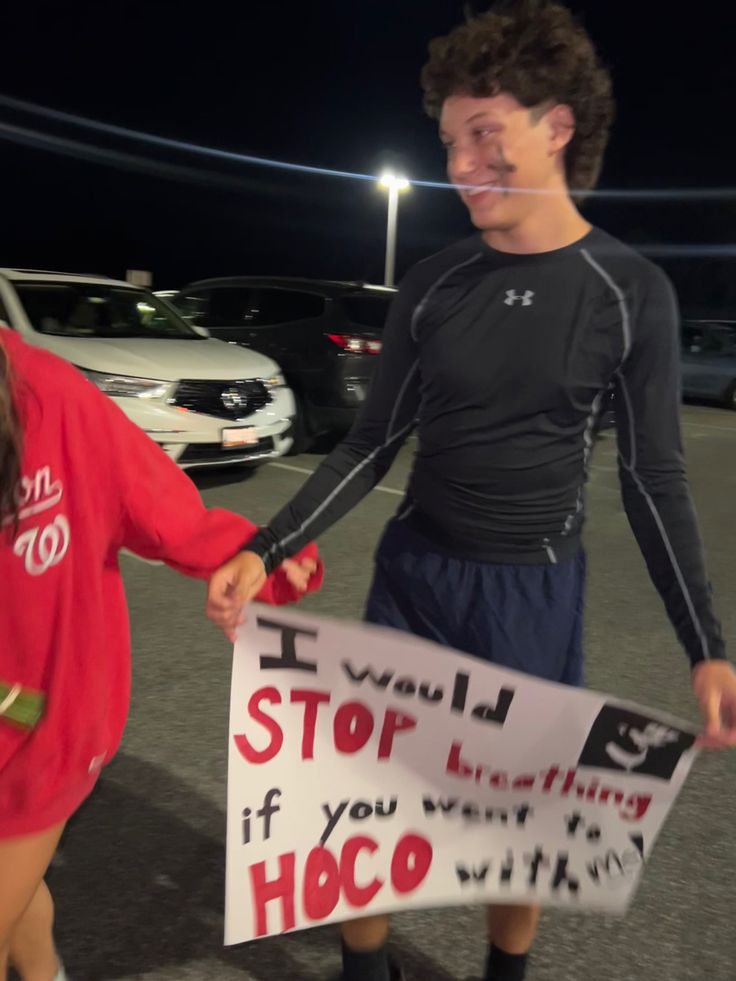 two young people holding hands while standing in a parking lot with a sign that says, i will stop everything if you want to hoco