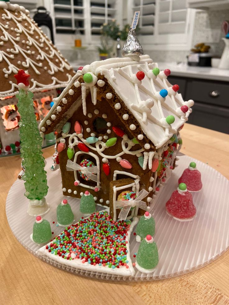 a gingerbread house decorated with sprinkles and christmas decorations on a plate