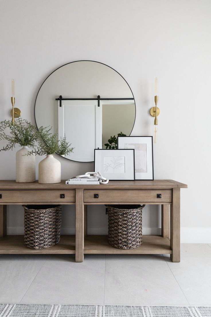 a wooden table topped with two baskets under a mirror