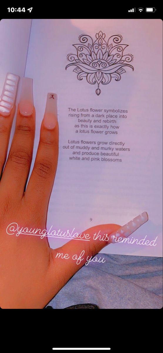 a woman's hand holding an open book in front of her face and writing on the page