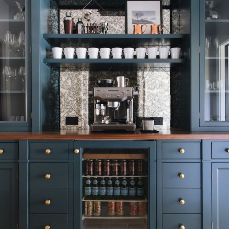 a coffee machine sitting on top of a wooden counter next to blue cabinets and drawers