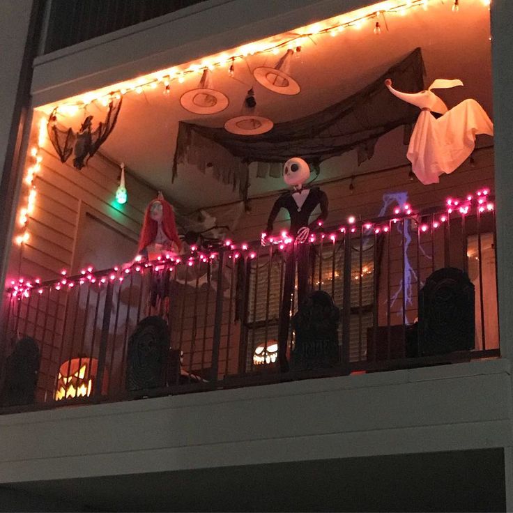 halloween decorations on the balcony of a house with lights and ghost heads hanging from the roof