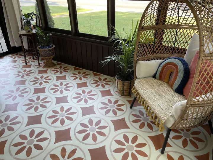 a porch with a swing chair and potted plants on the floor next to it