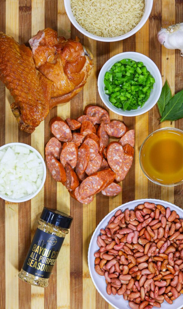 an assortment of food is displayed on a cutting board, including meats, beans and rice