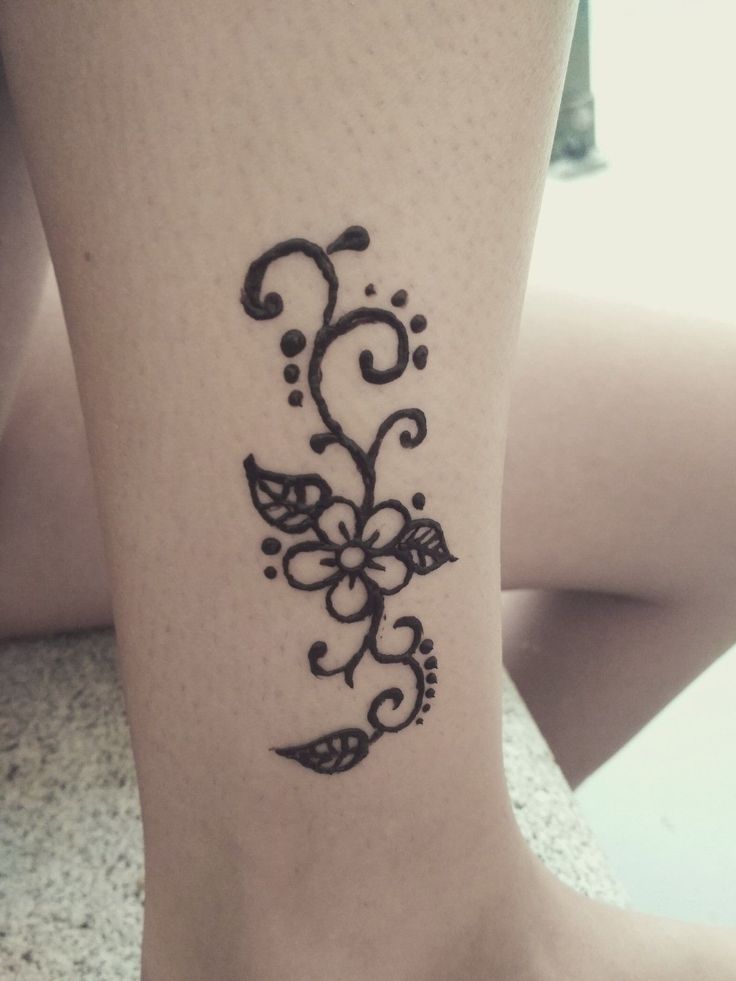 a woman's foot with a tattoo design on the side of her leg,