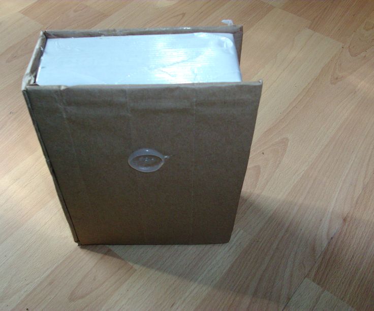 an open brown box sitting on top of a hard wood floor next to a wall