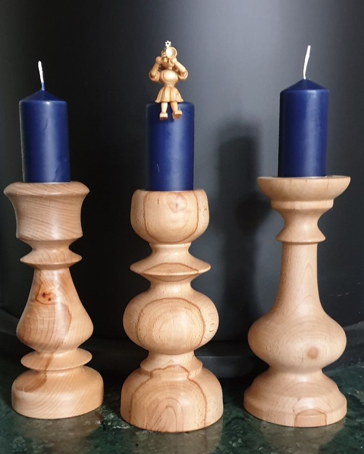 three wooden candlesticks with blue candles and a teddy bear figurine