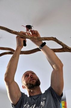 a man is holding up some branches with one hand and the other arm above his head