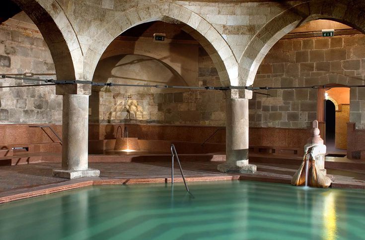 an indoor swimming pool surrounded by stone arches