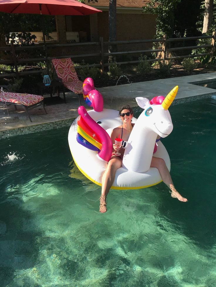 a woman is sitting on an inflatable unicorn float at the edge of a pool