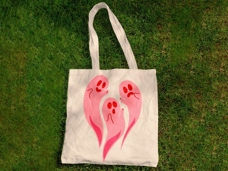 a white bag with pink and red designs on it sitting in the grass next to some green grass